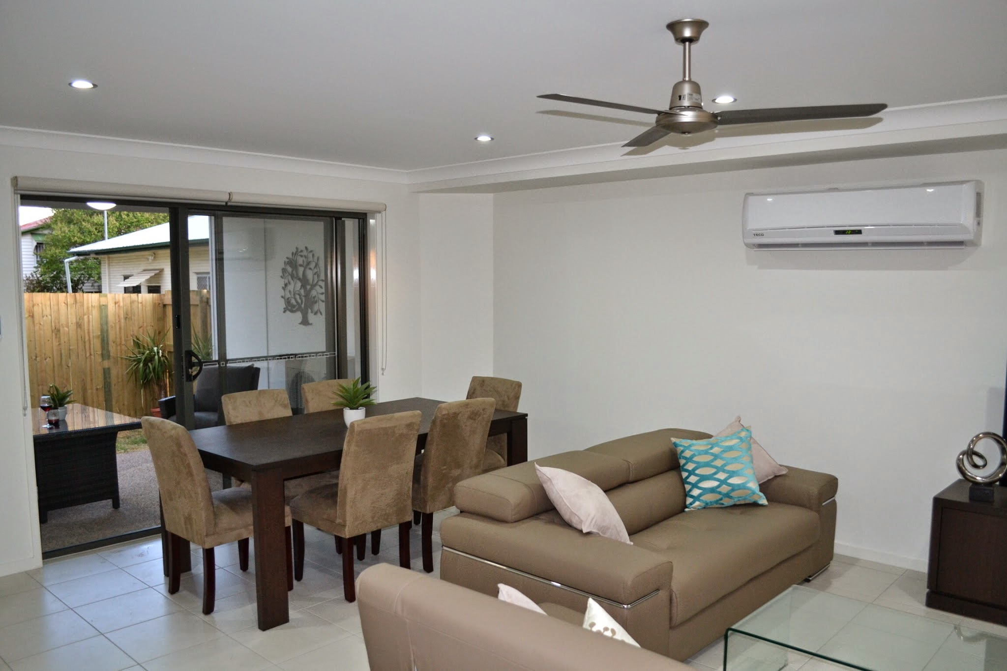 Open plan living and dining room with split-system air conditioning and a ceiling fan